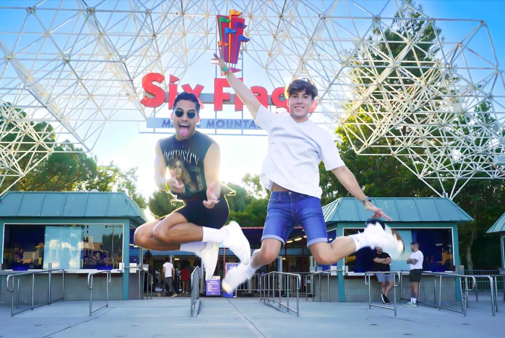 two boys jumping up in the air in front of Magic Mountain entrance with big smiles